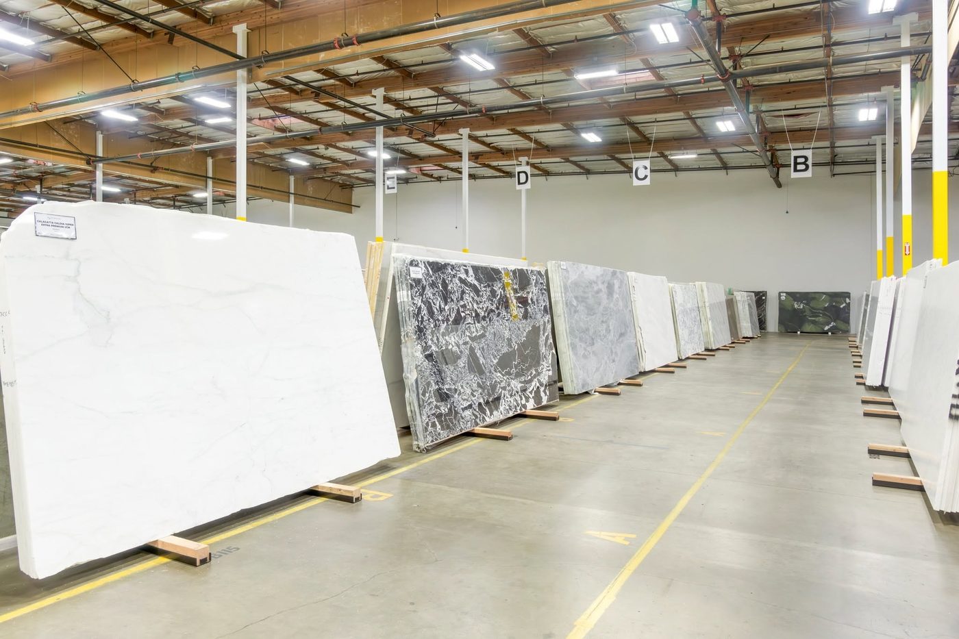 Stone gallery with full marble slabs standing on racks, including labeled Calacatta, for slab by slab selection